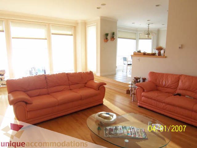 Bright living room with orange leather sofa, hardwood floors, and large windows. - 1659 Langton Place, West Vancouver