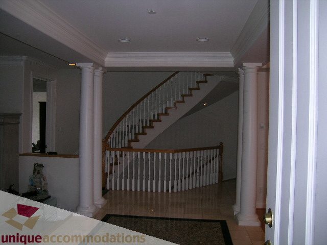 Staircase with white columns and wooden railings leading to upper floor. - 1659 Langton Place, West Vancouver