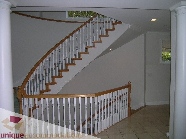 Staircase leading to upper floor with white railings and tiled flooring. - 1659 Langton Place, West Vancouver