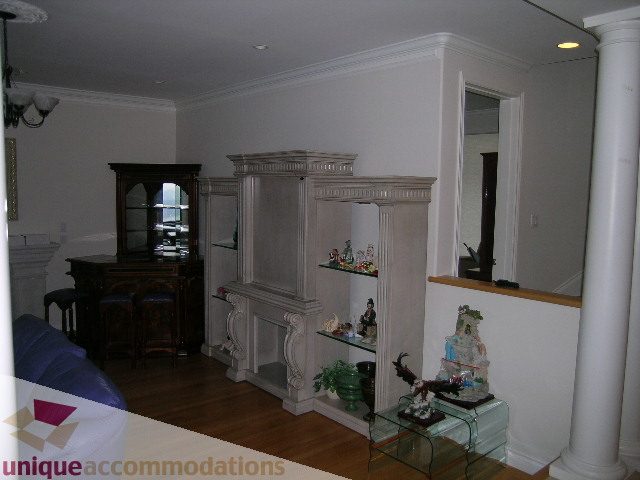 Spacious living room with white columns, hardwood floors, and a fireplace. - 1659 Langton Place, West Vancouver