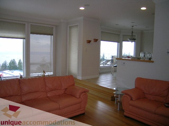 Spacious living room with hardwood floors, large windows, and a city view. - 1659 Langton Place, West Vancouver