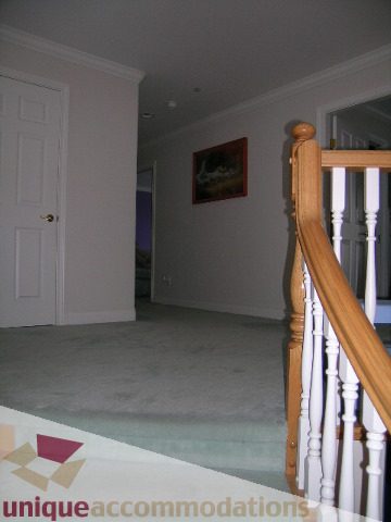 Furnished bedroom with wooden staircase and carpeted floor. - 1659 Langton Place, West Vancouver