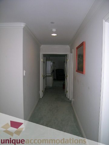 Narrow hallway with carpeted floor and orange-framed artwork. - 1659 Langton Place, West Vancouver
