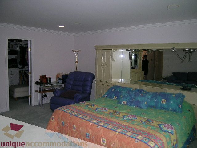 Spacious bedroom with mirrored closet and colorful bedding. - 1659 Langton Place, West Vancouver