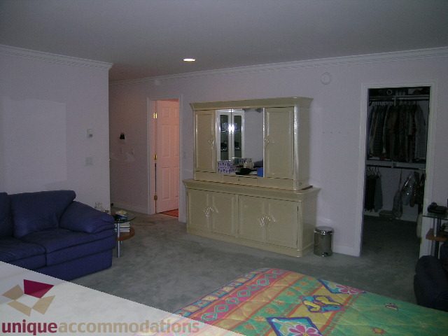 Living room with beige furniture, open closet, and carpeted floor. - 1659 Langton Place, West Vancouver