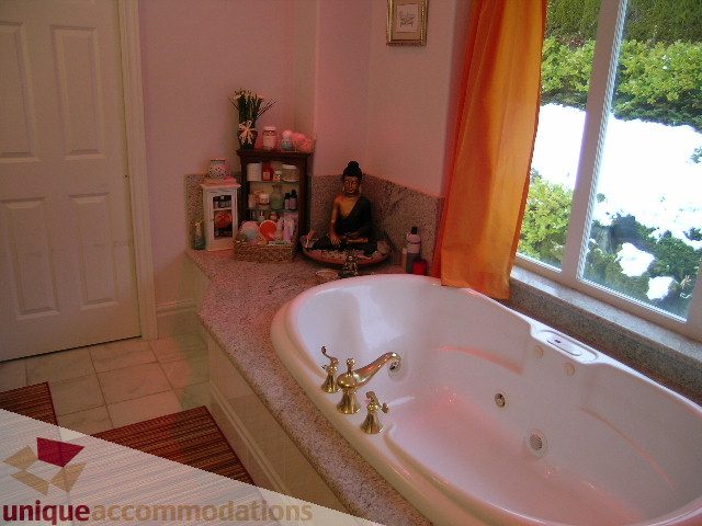 Spacious bathroom with marble countertops, a soaking tub, and a view of the ocean. - 1659 Langton Place, West Vancouver