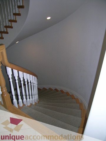Staircase with wooden banisters and carpeted steps leading up. - 1659 Langton Place, West Vancouver