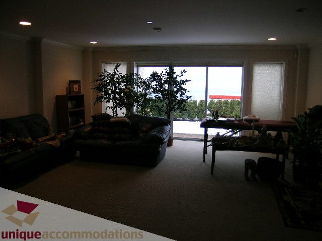 Spacious living room with large windows and outdoor view, modern furniture, and indoor plants. - 1659 Langton Place, West Vancouver