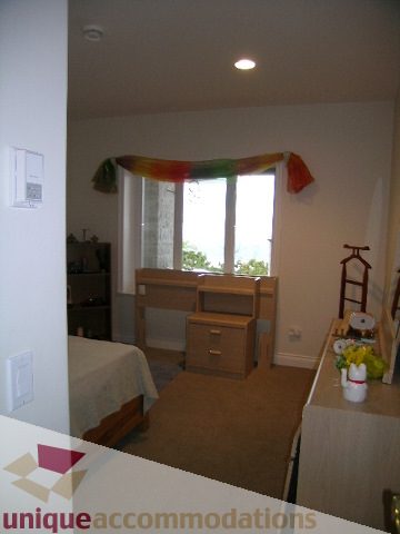 Bright living room with hardwood floors and a colorful scarf draped over a window. - 1659 Langton Place, West Vancouver
