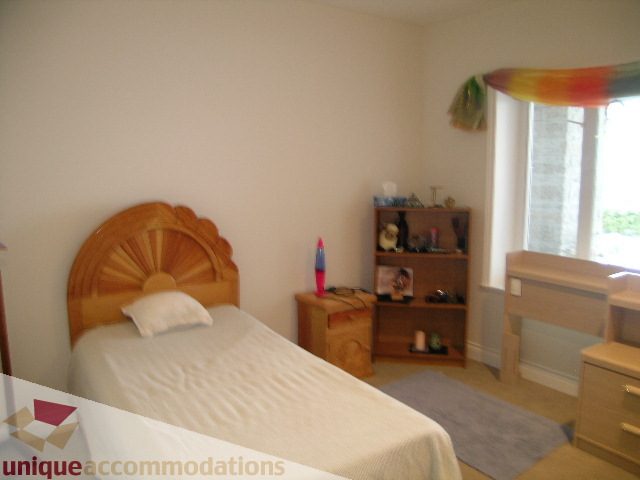 Bright bedroom with wooden headboard and window view. - 1659 Langton Place, West Vancouver