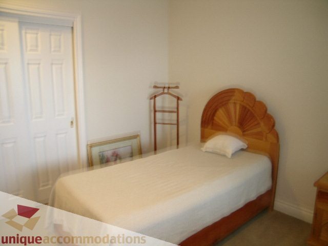 Bright bedroom with wooden headboard and white bedding. - 1659 Langton Place, West Vancouver