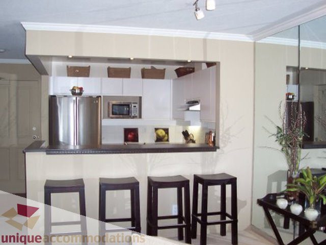 Bright kitchen with modern appliances, bar stools, and a city view. - 313-525 Wheelhouse Square, Vancouver West Side