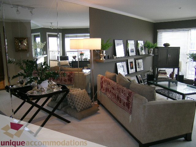 Furnished living room with mirrored walls, modern furniture, and city view. - 313-525 Wheelhouse Square, Vancouver West Side