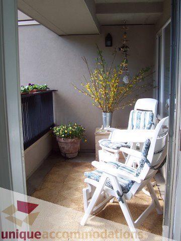 Furnished balcony with white chairs, yellow flowering plant, and cozy rug. - 313-525 Wheelhouse Square, Vancouver West Side
