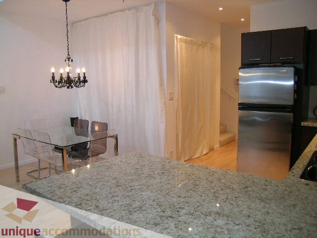 Bright kitchen with granite countertops and modern appliances, open to a dining area with a chandelier. - 1135 Seymour Street, Vancouver Downtown