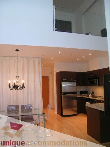 Bright kitchen with dark cabinetry and hardwood floors, open to a dining area with glass table. - 1135 Seymour Street, Vancouver Downtown