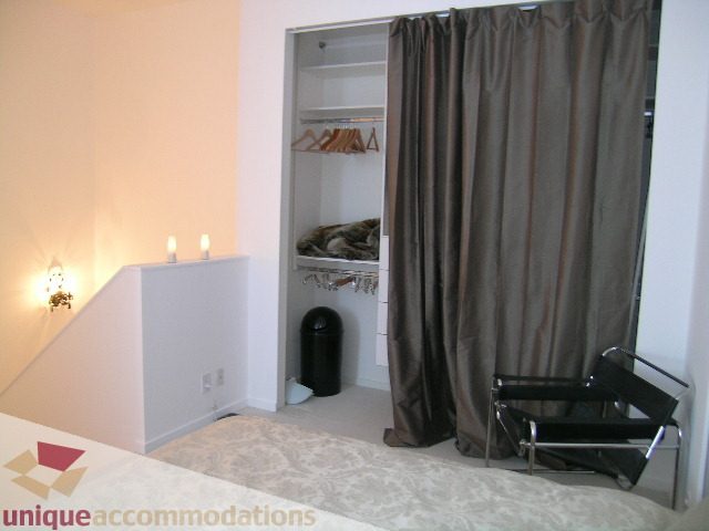 Furnished bedroom with closet and chair, lighted wall sconce. - 1135 Seymour Street, Vancouver Downtown