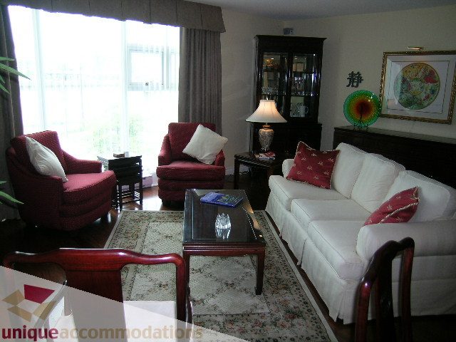 Bright living room with white couch, red armchairs, and a large window. - 305 - 1030 Quebec Street, Vancouver Downtown