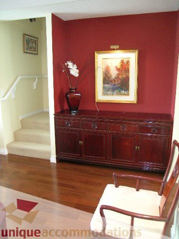 Living room with hardwood floors, red accent wall, and framed artwork. - 305 - 1030 Quebec Street, Vancouver Downtown