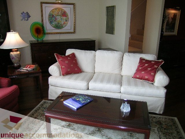 Furnished living room with white couches, red pillows, and a dark wood coffee table. - 305 - 1030 Quebec Street, Vancouver Downtown