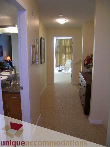 Bright kitchen with granite countertops and hardwood floors, leading to a cozy living area with a city view.