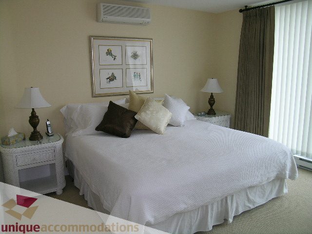 Furnished bedroom with two twin beds, white bedding, and a framed artwork above. - 305 - 1030 Quebec Street, Vancouver Downtown