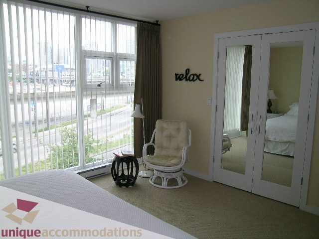 Spacious bedroom with large windows offering a city view and a "relax" sign on the wall. - 305 - 1030 Quebec Street, Vancouver Downtown