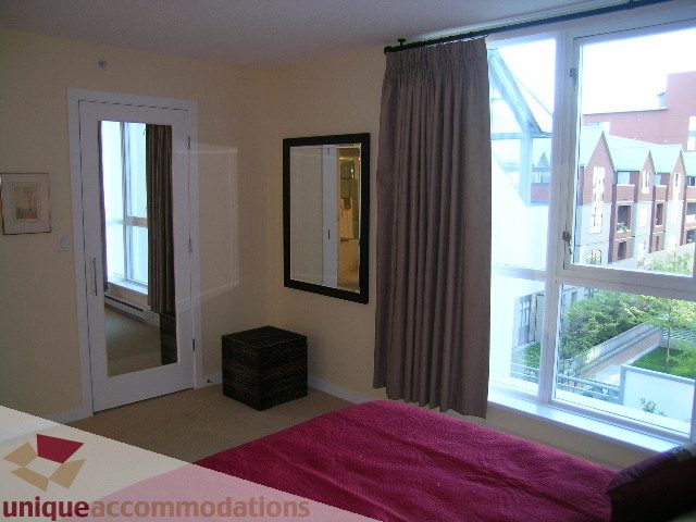 Bright bedroom with large windows, city view, and a cozy bed setup. - 305 - 1030 Quebec Street, Vancouver Downtown