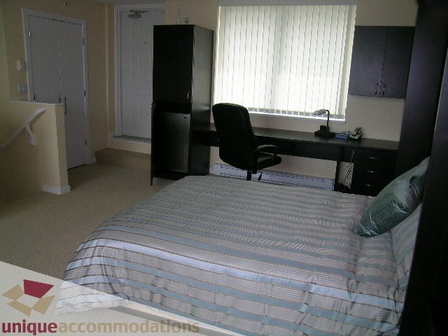 Bright bedroom with striped bedding and desk setup. - 305 - 1030 Quebec Street, Vancouver Downtown