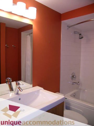 Furnished bathroom with orange walls, white sink, and bathtub. - 2234 York Ave, Vancouver West Side