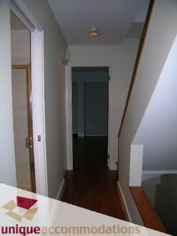 Furnished hallway with hardwood floors and a wooden banister leading to the second floor. - 2234 York Ave, Vancouver West Side