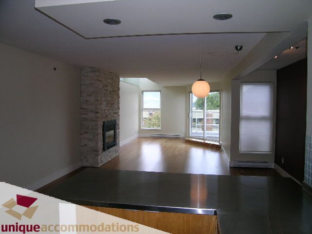 Open-concept living area with hardwood floors and a modern fireplace. - 2234 York Ave, Vancouver West Side