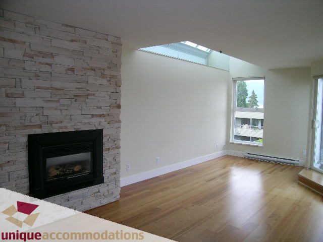 Spacious living room with hardwood floors, stone fireplace, and skylight. - 2234 York Ave, Vancouver West Side