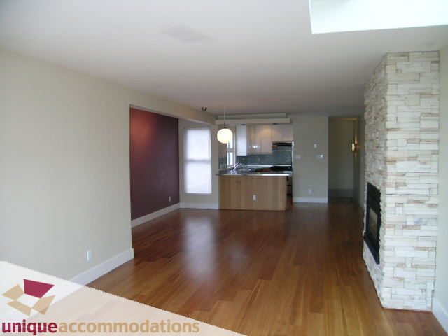 Open-concept living space with hardwood floors and a stone fireplace. - 2234 York Ave, Vancouver West Side