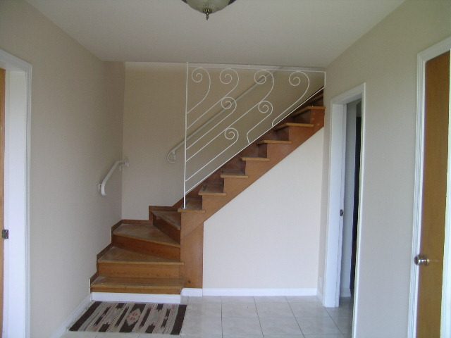 Staircase leading to upper level with white railing and wooden steps. - 660 Blueridge Ave, North Vancouver