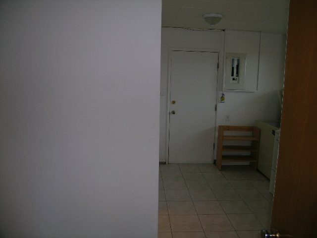 Spacious kitchen with white cabinets and tiled floor, featuring a small breakfast bar. - 660 Blueridge Ave, North Vancouver
