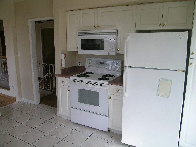 Bright kitchen with white appliances, granite countertops, and tiled flooring. - 660 Blueridge Ave, North Vancouver