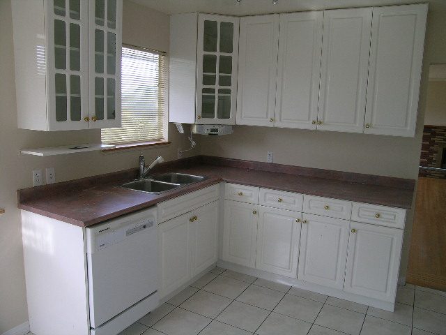 Bright kitchen with white cabinets, dark countertops, and a window view. - 660 Blueridge Ave, North Vancouver