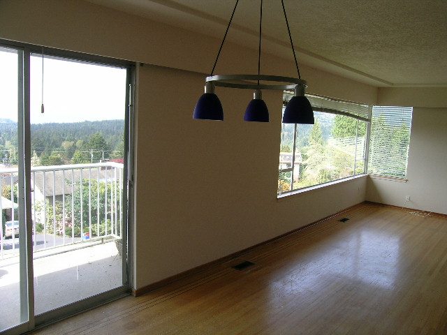 Spacious living room with hardwood floors, large windows, and a stunning city view. - 660 Blueridge Ave, North Vancouver