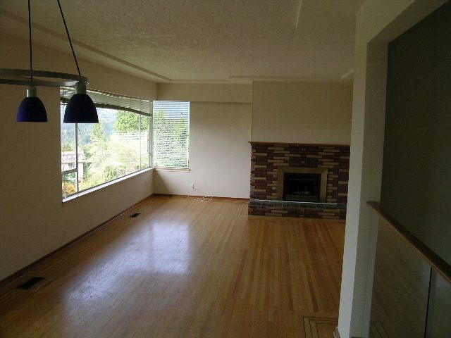 Spacious living room with hardwood floors, large windows, and a modern fireplace. - 660 Blueridge Ave, North Vancouver