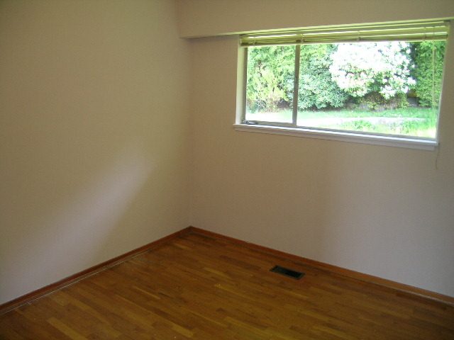 Spacious bedroom with hardwood floors and a large window overlooking greenery. - 660 Blueridge Ave, North Vancouver