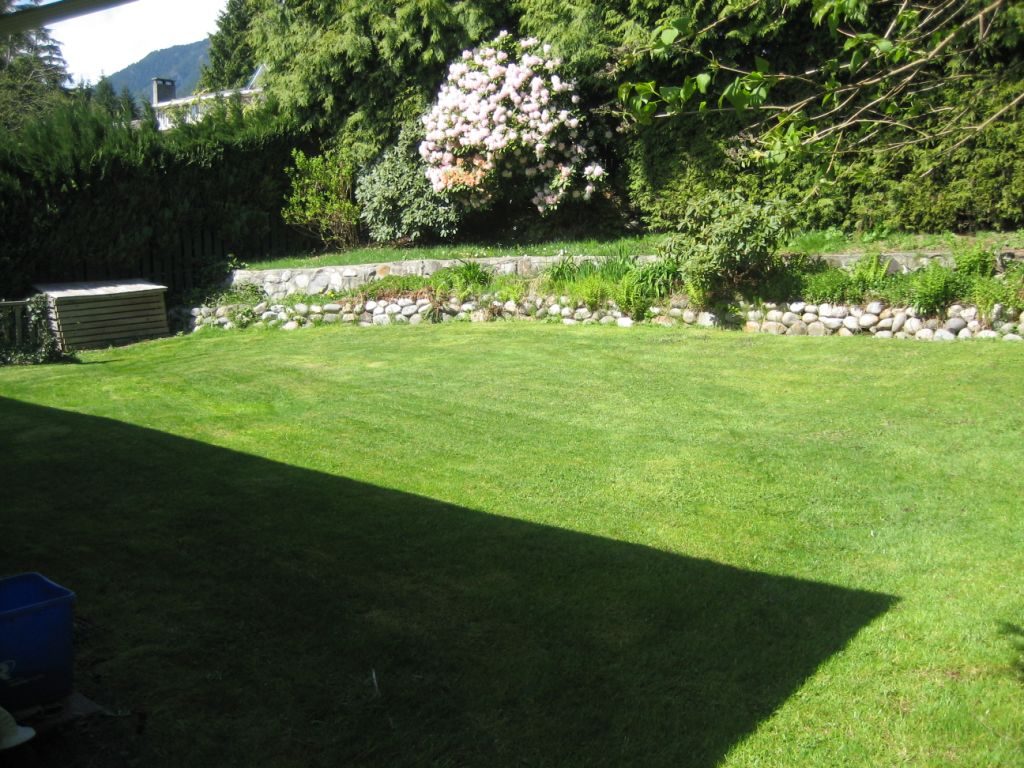 Spacious backyard with lush green lawn and blooming flowers. - 660 Blueridge Ave, North Vancouver