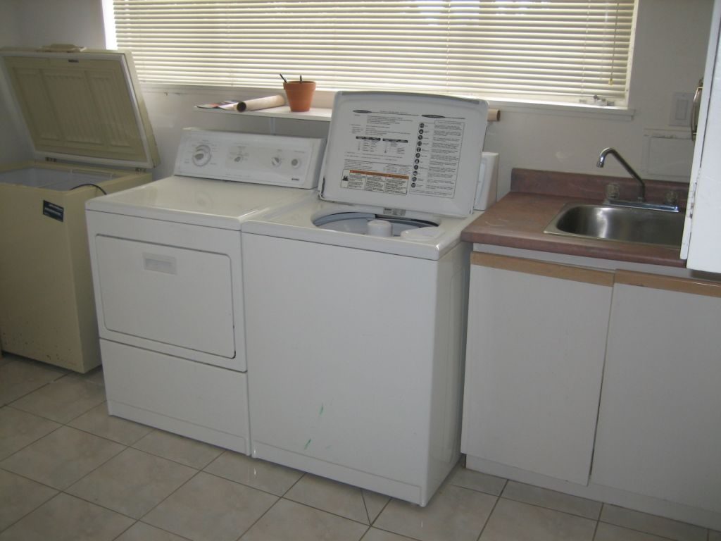 Bright laundry room with white washer and dryer, wooden countertops, and a sink. - 660 Blueridge Ave, North Vancouver