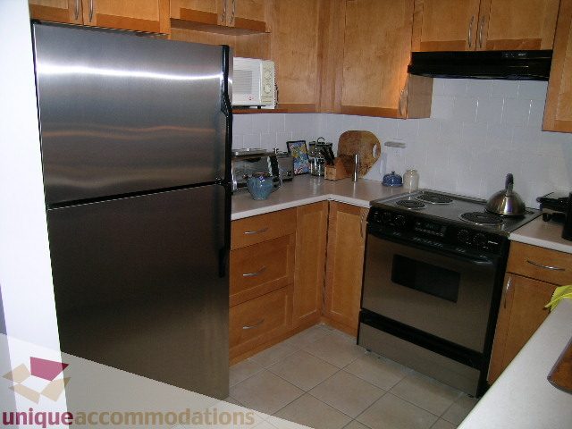 Bright kitchen with stainless steel appliances, light wood cabinets, and tiled backsplash. - 201-365 E 1st Ave, North Vancouver