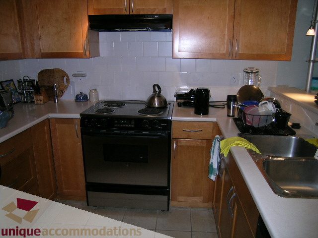 Bright kitchen with light wood cabinets, stainless steel appliances, and granite countertops. - 201-365 E 1st Ave, North Vancouver
