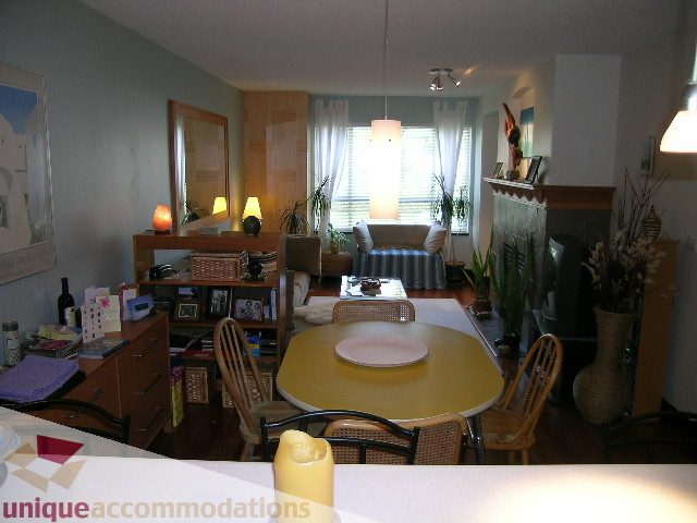 Furnished living room with hardwood floors, large windows, and a cozy ambiance. - 201-365 E 1st Ave, North Vancouver
