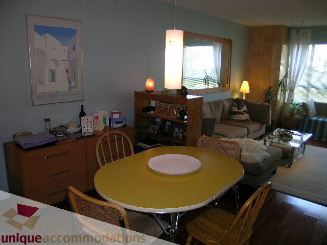 Furnished dining area with modern table, chairs, and pendant light; hardwood floors. - 201-365 E 1st Ave, North Vancouver