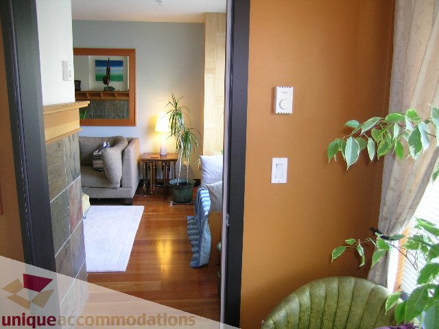 Furnished living room with hardwood floors, cozy seating, and a view of the city. - 201-365 E 1st Ave, North Vancouver