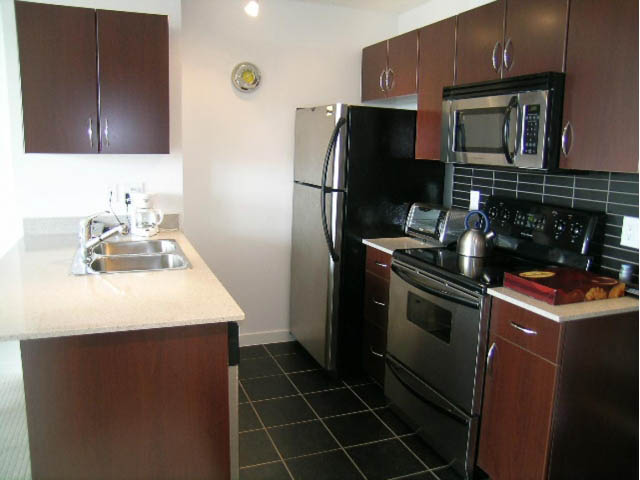 Modern kitchen with granite countertops, stainless steel appliances, and dark wood cabinets. - 2021 - 938 Smithe Street, Vancouver Downtown
