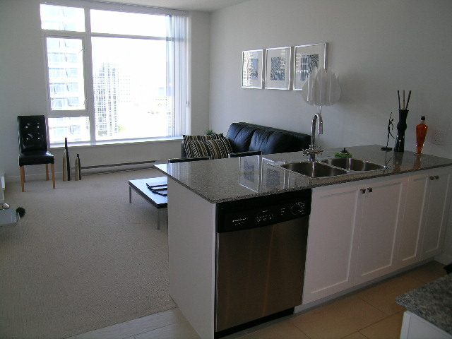 Bright kitchen with granite countertops, stainless steel appliances, and a cozy living area featuring a black leather...